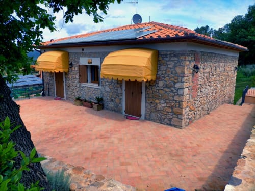 Cottage in pietra con tende gialle e patio in cotto a La Casetta di Pietra, Gavorrano, Italia