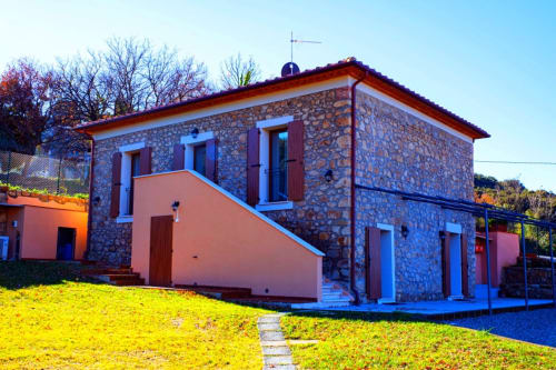 La Casetta di Pietra, casa in pietra con vista sul giardino a Gavorrano, caratterizzata da accenti in terracotta e persiane blu