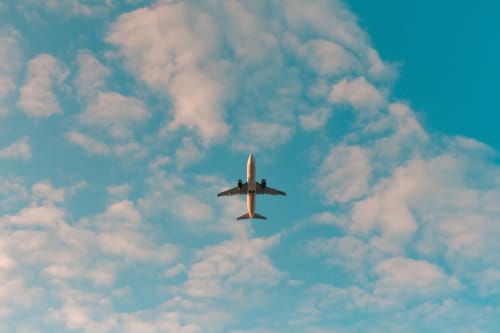 Airplane flying over clouds, representing travel to Posada, Italy and B&B Eleonora D'Arborea accommodation