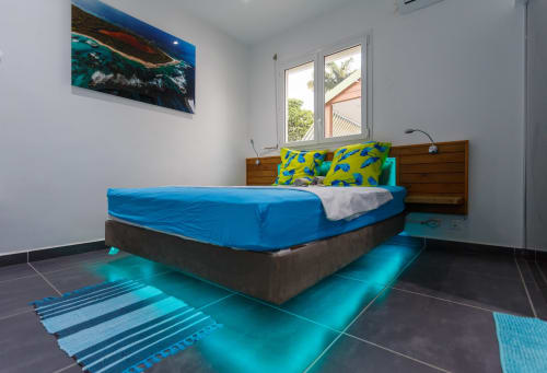 Chambre lumineuse à Kaz A Bibi à Sainte-Rose avec literie bleue, accents turquoise et décoration thématique océan.