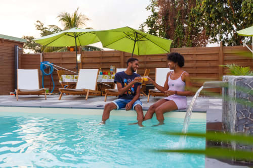 Couple savourant des verres à la piscine de l'hôtel-boutique Kaz A Bibi à Sainte-Rose, Guadeloupe