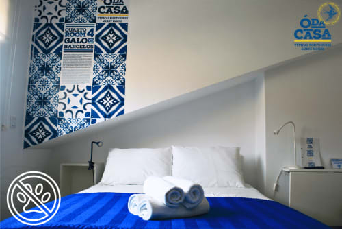 Quarto Galo de Barcelos na pousada Ó da Casa em Peniche com azulejos azuis tradicionais, roupa branca e vista para a cidade