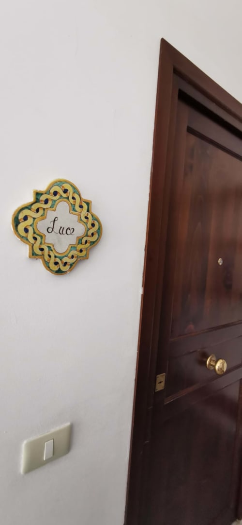 Decorative nameplate marked 'Luce' on white wall next to dark wooden door at Casa Bellini apartment in Palermo