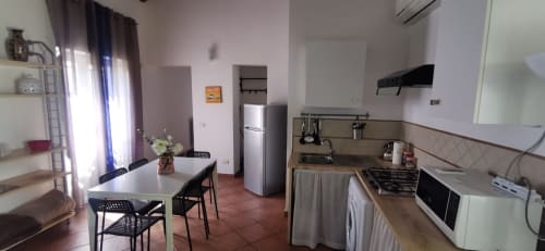 Casa Bellini Apartment Luce kitchen and dining area in Palermo with dining table, refrigerator, and cooking appliances