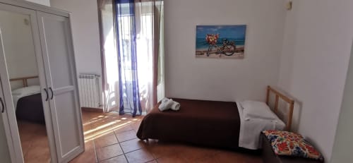 Bright bedroom in Casa Bellini apartment in Palermo with bed, balcony access, wardrobe, and beach artwork