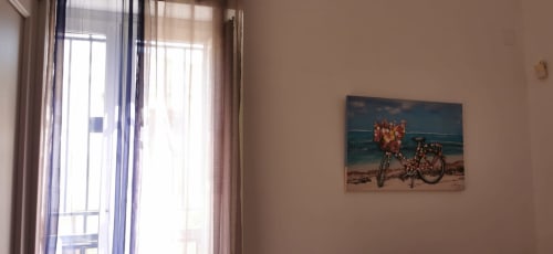 Bright apartment interior with open glass doors, beige walls, and beach-themed bicycle artwork at Casa Bellini in Palermo