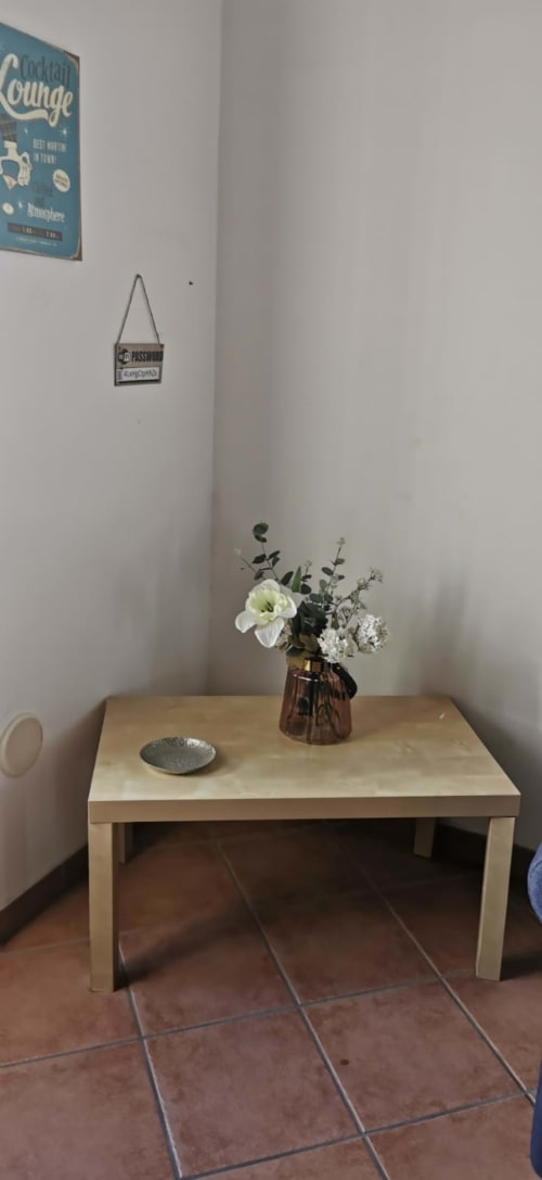 Minimalist dining table in Casa Bellini apartment with white flowers and terracotta tile flooring in Palermo