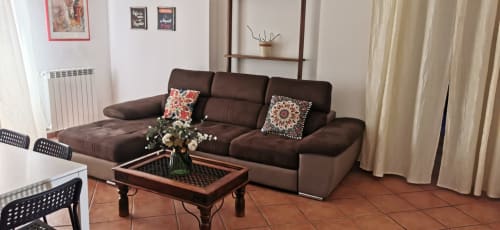 Modern brown leather sofa in Perla Apartment at Casa Bellini, Palermo, with decorative pillows and city view