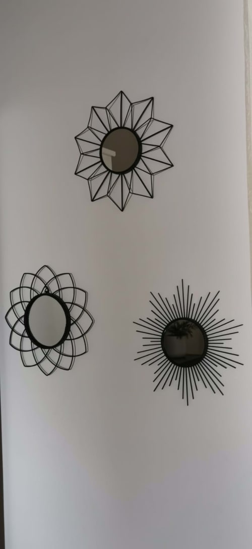 Three decorative geometric sunflower mirrors with dark centers and line-drawn petals on white wall at Casa Bellini apartment