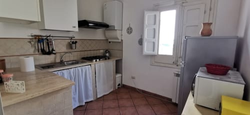 Kitchen and dining area in Perla Apartment at Casa Bellini, Palermo, featuring cooking appliances, dining table, and modern