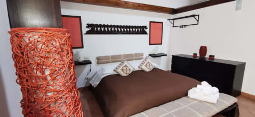 Modern bedroom at Casa Bellini Perla Apartment in Palermo with brown bed, red sculptural lamp, and contemporary wall art