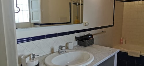 Modern bathroom in Perla Apartment at Casa Bellini, Palermo, featuring marble countertop, round sink, and navy tile accents