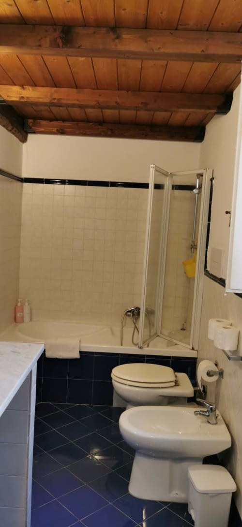 Bathroom in Perla Apartment at Casa Bellini Palermo with shower enclosure, toilet, bidet, and wooden ceiling beams