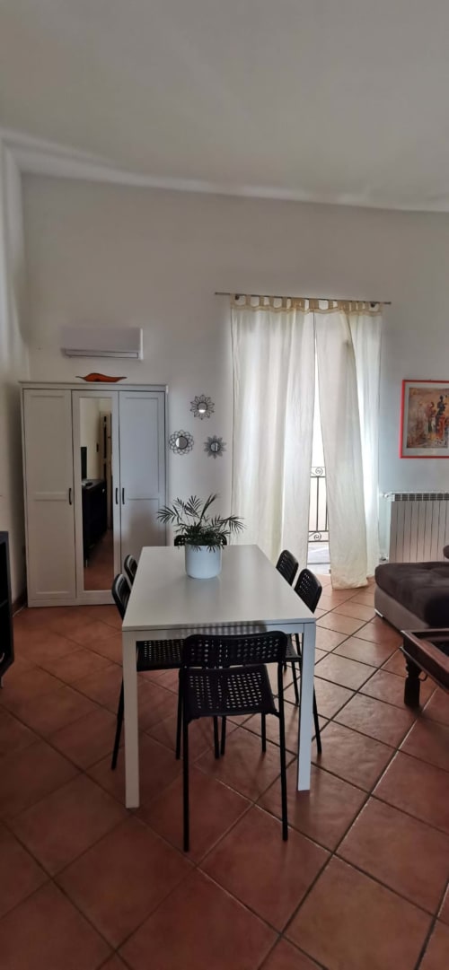 Dining room in Casa Bellini's Perla Apartment, Palermo, with white table, black chairs, and city view doors
