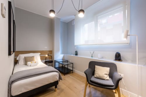 Camera moderna di Casa Lounge Istria a Cagliari con letto, poltrona, lampade a sospensione e vista sulla città dalle finestre