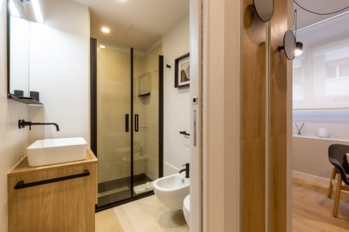 Moderno bagno di Casa Lounge Istria a Cagliari con vanity in legno, lavabo a vessel, doccia con box in vetro e piastrelle bianche