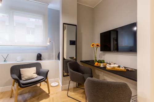 Camera moderna di Casa Lounge Istria a Cagliari con sedie grigie, TV nera, girasoli e vista sulla città