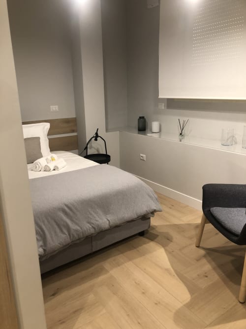 Camera moderna a Casa Lounge Istria a Cagliari con biancheria grigia, pavimento in legno e vista sulla città