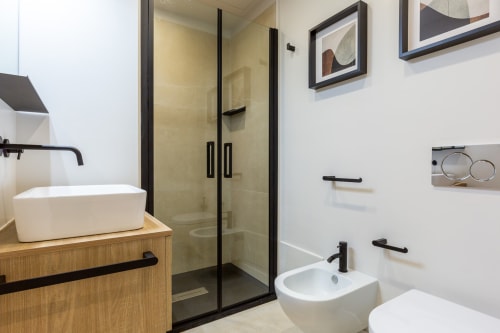 Bagno moderno di CASA LOUNGE ISTRIA a Cagliari con doccia con cornice nera, doppio lavabo e mobile in legno