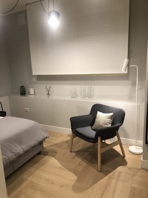 Moderna camera da letto a Casa Lounge Istria a Cagliari con poltrona grigio scuro, letto e mensole bianche minimaliste