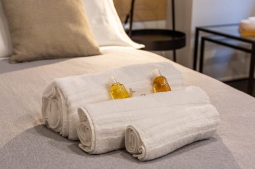 Asciugamani bianchi arrotolati con bottiglie di amenities dorate sul letto di Casa Lounge Istria, Cagliari