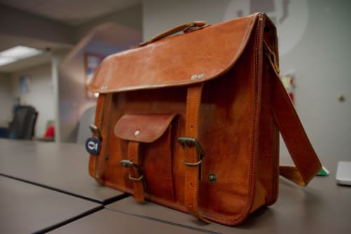 Vieux sac cartable en cuir marron posé sur un bureau à Locations Loc'Maria, Belle Île en Mer