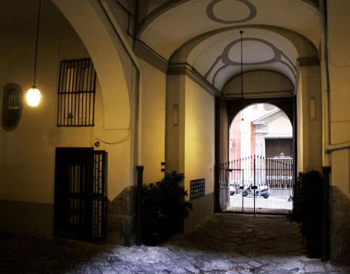 Elegant Italian courtyard entrance with arched ceiling, yellow walls, and gate leading to B&B Il Conservatorio in Naples