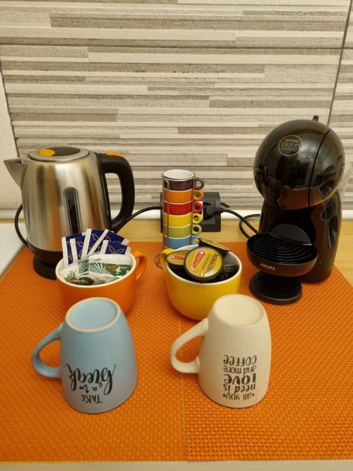 Coffee maker, electric kettle, and colorful mugs on orange table at B&B Il Conservatorio Naples apartment