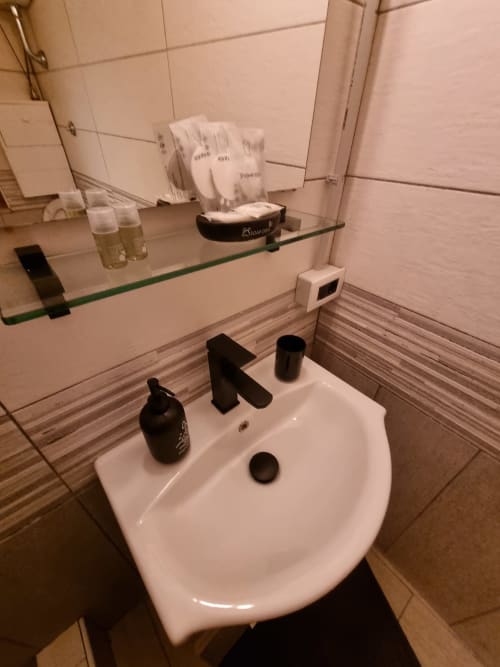 Modern bathroom in Majorana apartment at B&B Il Conservatorio Naples, featuring white sink, black fixtures, glass mirror