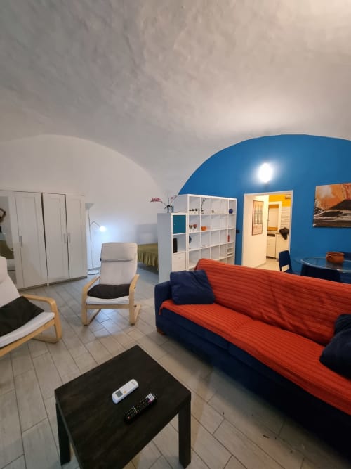 Spacious apartment living area at B&B Il Conservatorio Naples with blue dome ceiling, red sofa, and modern furnishings.