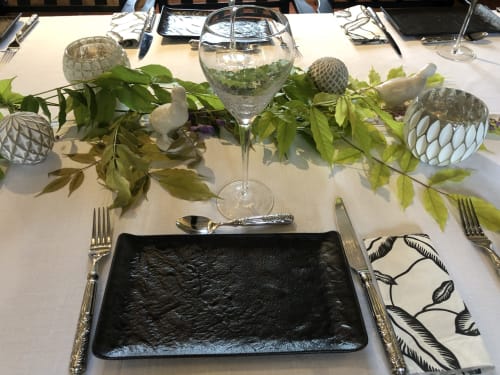 Elegant table setting at Moulin De La Chevrière with black plate, greenery, water glasses, and decorative items