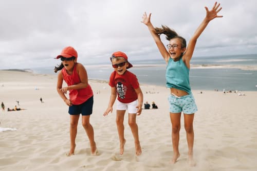 enfants sautent sur la dune du pyla, proximité de l'aérogrange séjour en famille été comme hiver à Biscarrosse Landes