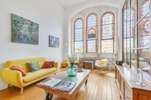 Chambre lumineuse et contemporaine à La Maison D'olivier avec canapé jaune, vitraux et vue sur les monuments à Mesnard la