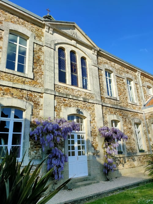 La chapelle de La Maison D'olivier avec ses fleurs de glycine pourpre et portes bleues à Mesnard la Barotière, France