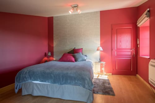 Chambre rouge vif avec literie bleue et oreillers roses à la Conciergerie Des Climats à Beaune, France