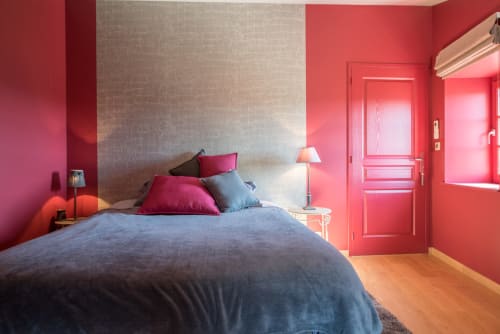 Chambre moderne à la Conciergerie Des Climats à Beaune avec murs rose vif, lit bleu et porte rouge