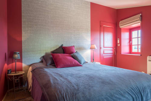 Chambre rouge éclatante à la Conciergerie Des Climats à Beaune avec lit queen, mur en briques blanches et mobilier moderne