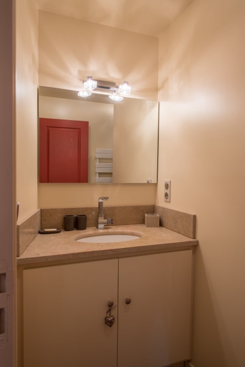 Salle de bains moderne avec caissonnerie beige et plan de travail en pierre à l'appartement Conciergerie Des Climats à Beaune, France