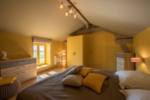 Chambre mansardée jaune vif à la Conciergerie Des Climats à Beaune, avec mobilier en bois et vue sur les montagnes