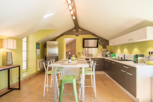 Cuisine-salle à manger jaune vif à Beaune avec bar blanc, placards bruns et plafond voûté