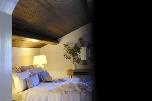 Cozy bedroom at Villa Várzea B&B in Várzea, Portugal with warm lighting, striped pillows, and wooden ceiling.