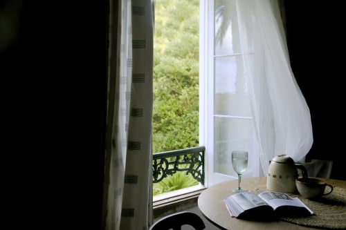 Villa Várzea B&B room with open French doors, white sheer curtains, tea service, and lush garden views in Várzea, Portugal