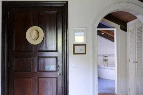 Dark wooden door with straw hat at Villa Várzea guesthouse in Várzea, Portugal, leading to bright interior spaces