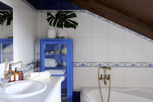 Elegant bathroom at Villa Várzea with blue cabinet, white tiles, brass fixtures and monstera plant in Várzea, Portugal