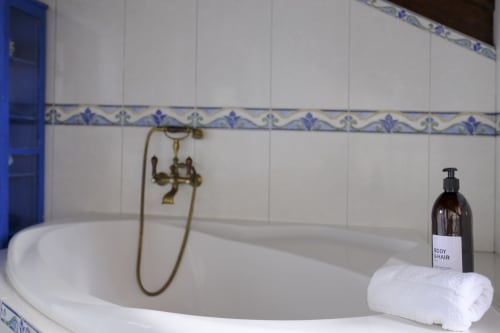 Elegant bathroom at Villa Várzea with white tiles, decorative blue border, brass faucet, and amenities in Várzea, Portugal