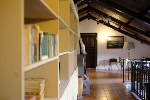 Bright attic bedroom at Villa Várzea with shelving, exposed beams, and traditional Portuguese decor