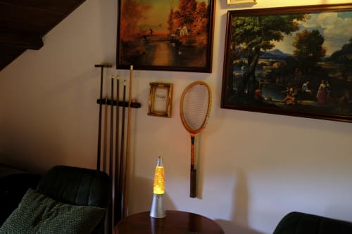 Villa Várzea bedroom wall with vintage tennis racket, paintings, lava lamp, and decorative items