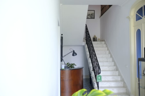 Villa Várzea entrance hall with marble staircase, black railing, wooden console table, and blue door in Várzea