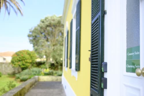 Exterior of Villa Várzea B&B showing yellow-painted building with green shutters and suite signs in Várzea, Portugal