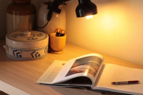 Warm desk setup at Villa Várzea's Nomad Nest with magazine, pen, and decorative items under task lighting